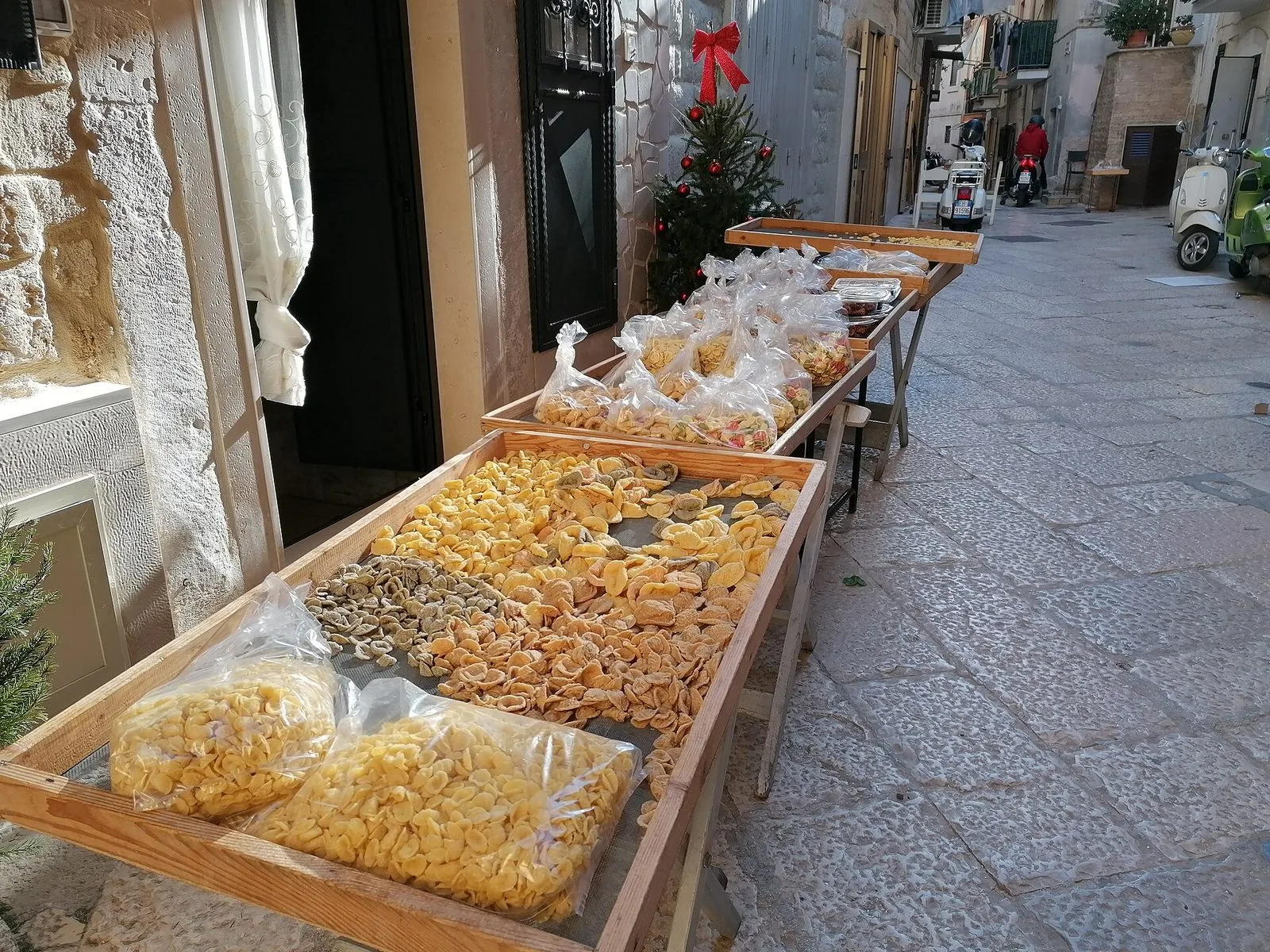Tavolieri di legno con orecchiette fresche messe ad asciugare in un vicolo lastricato di Bari vecchia